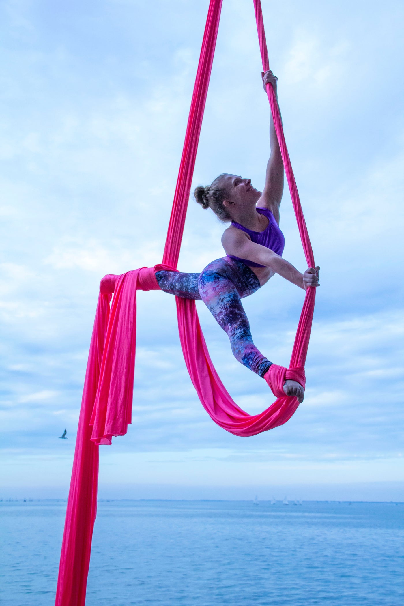 Instructor performs aerial silks high over the water