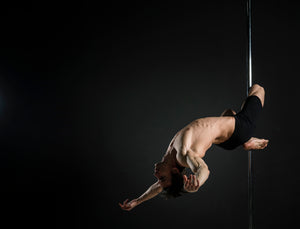 Pole acrobat does tricks on dance pole